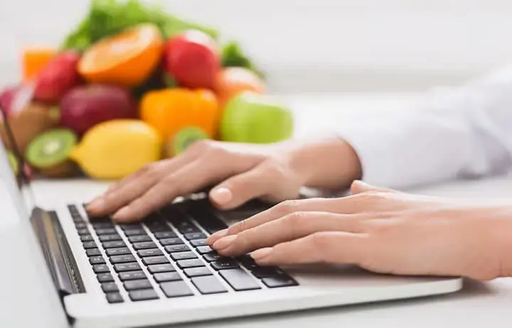 Hands on keyboard with produce in background